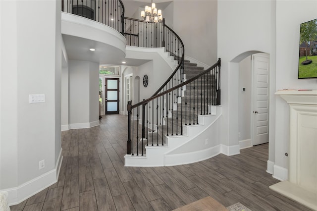 2736 Ahnya Ln, League City, TX 77573 - stairway featuring arched walkways, a high ceiling, wood finished floors, a chandelier, and baseboards
