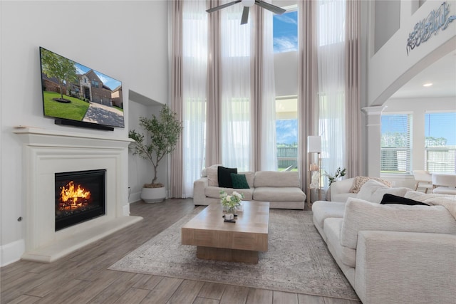 2736 Ahnya Ln, League City, TX 77573 - living area featuring arched walkways, wood finished floors, a ceiling fan, a lit fireplace, and a towering ceiling