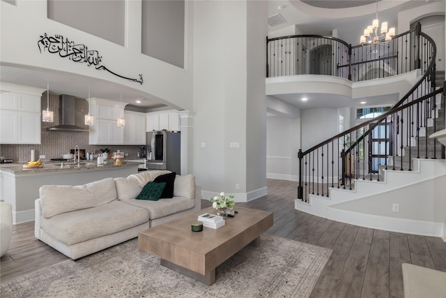 2736 Ahnya Ln, League City, TX 77573 - living room featuring a chandelier, a towering ceiling, baseboards, wood finished floors, and stairway