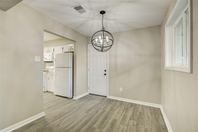 unfurnished dining area featuring light wood finished floors, visible vents, baseboards, and an inviting chandelier