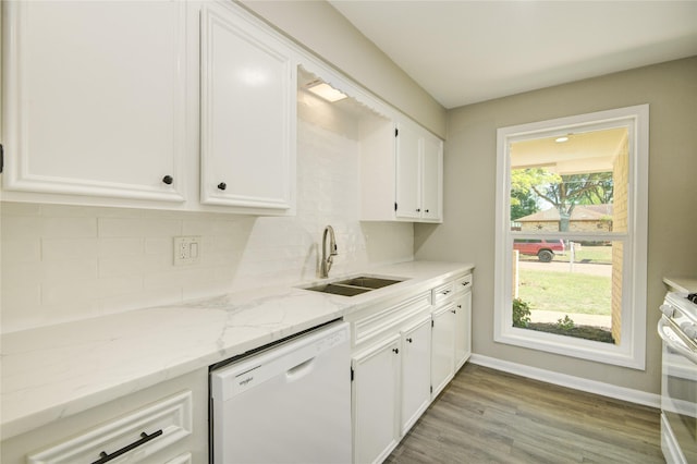 kitchen with white appliances, tasteful backsplash, white cabinets, a sink, and baseboards
