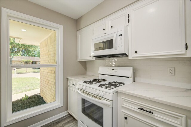 kitchen featuring white cabinets, white appliances, wood finished floors, light stone countertops, and backsplash