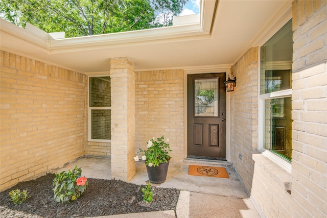 doorway to property with a porch and brick siding