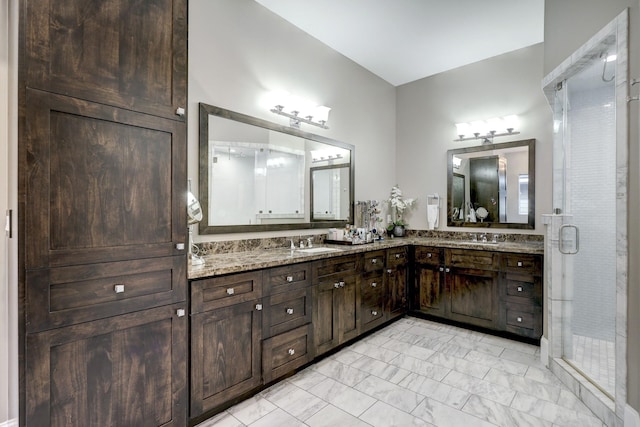bathroom featuring a shower stall, double vanity, marble finish floor, and a sink