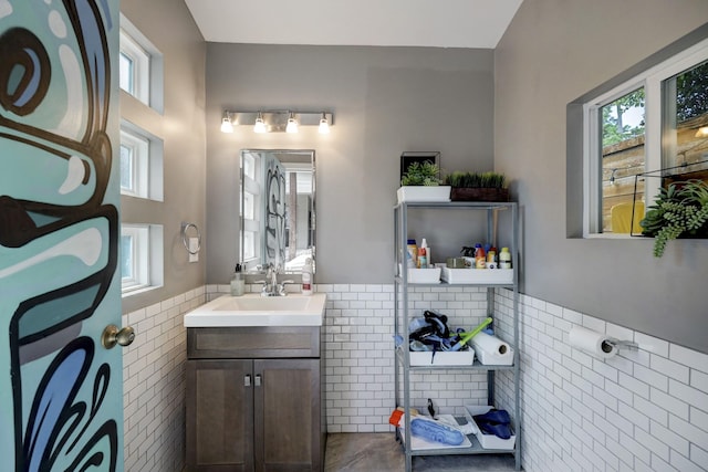 bathroom featuring a wainscoted wall, plenty of natural light, and tile walls
