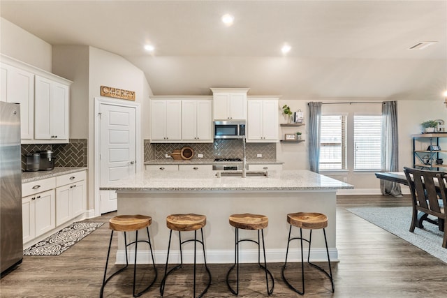 21718 Rose Maris Ln, Tomball, TX 77377 - kitchen featuring an island with sink, lofted ceiling, white cabinetry, and appliances with stainless steel finishes
