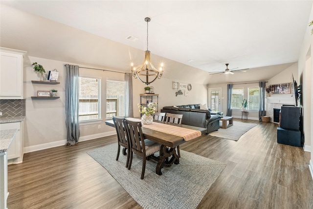 21718 Rose Maris Ln, Tomball, TX 77377 - dining area featuring ceiling fan with notable chandelier, a fireplace, wood finished floors, lofted ceiling, and baseboards