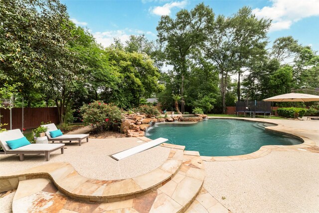 view of pool with a patio, a pool with connected hot tub, fence, and a trampoline