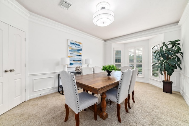dining room with visible vents, light carpet, ornamental molding, and a decorative wall