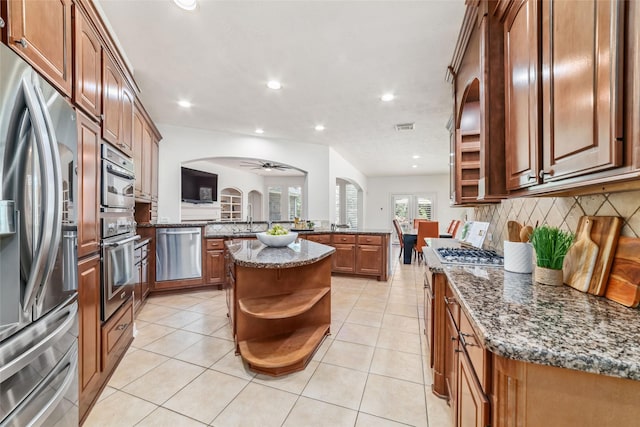 kitchen featuring ceiling fan, backsplash, appliances with stainless steel finishes, open shelves, and a peninsula