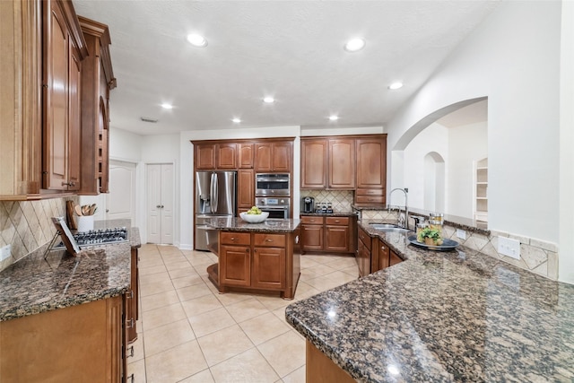 kitchen with stainless steel appliances, a center island, a sink, and tasteful backsplash