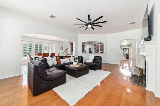 living room featuring visible vents, arched walkways, ceiling fan, and stairway