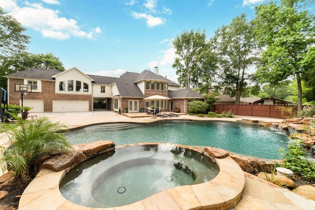view of pool featuring a pool with connected hot tub, fence, and a patio area