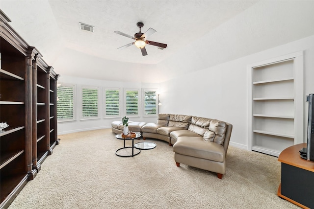 living area featuring visible vents, a ceiling fan, baseboards, a tray ceiling, and carpet flooring