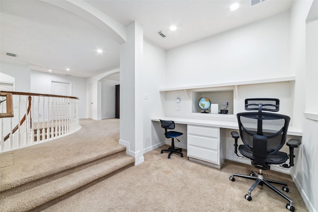 carpeted office featuring arched walkways, visible vents, built in desk, and recessed lighting