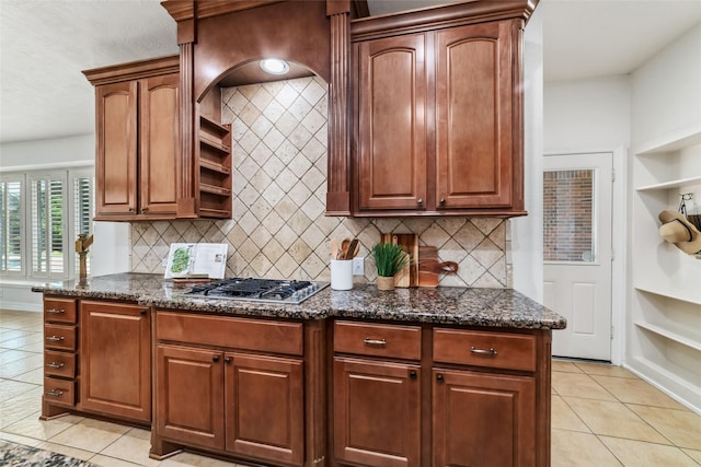 kitchen with open shelves, decorative backsplash, stainless steel gas cooktop, and dark stone countertops