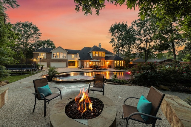 view of patio / terrace with a trampoline, an outdoor fire pit, and a pool with connected hot tub