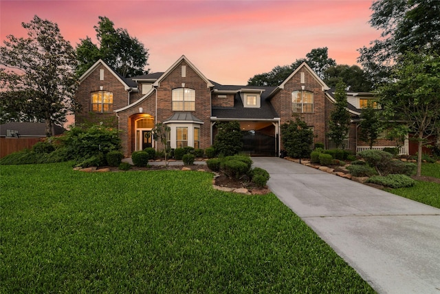 traditional-style house featuring a lawn, concrete driveway, and brick siding