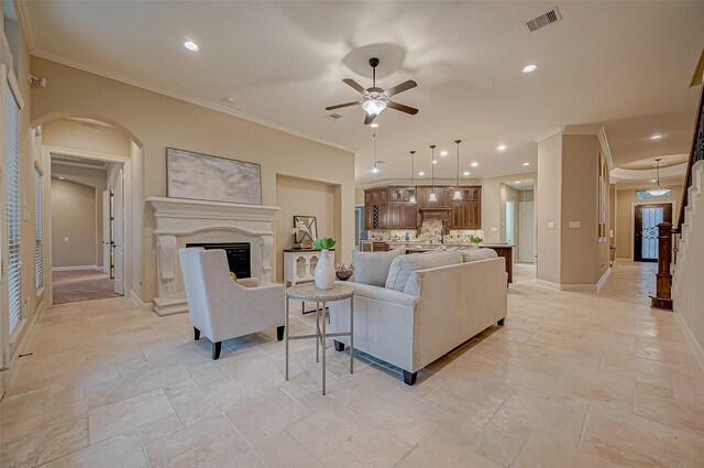 3215 Wimberly Place Ln, Katy, TX 77494 - living area featuring arched walkways, a ceiling fan, stone tile floors, ornamental molding, and a fireplace with raised hearth