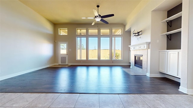 2135 Llerena Ln, League City, TX 77573 - unfurnished living room featuring a ceiling fan, wood finished floors, a tiled fireplace, and baseboards