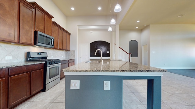 2135 Llerena Ln, League City, TX 77573 - kitchen with stainless steel appliances, a sink, arched walkways, light stone countertops, and decorative backsplash