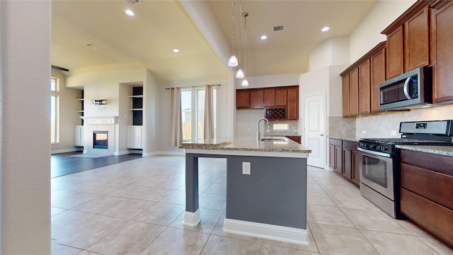 2135 Llerena Ln, League City, TX 77573 - kitchen with appliances with stainless steel finishes, a sink, light tile patterned floors, light stone counters, and recessed lighting