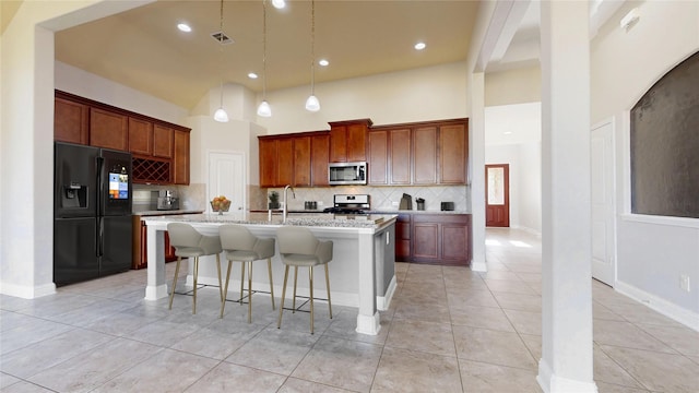 2135 Llerena Ln, League City, TX 77573 - kitchen featuring appliances with stainless steel finishes, tasteful backsplash, a breakfast bar, light tile patterned floors, and a center island with sink