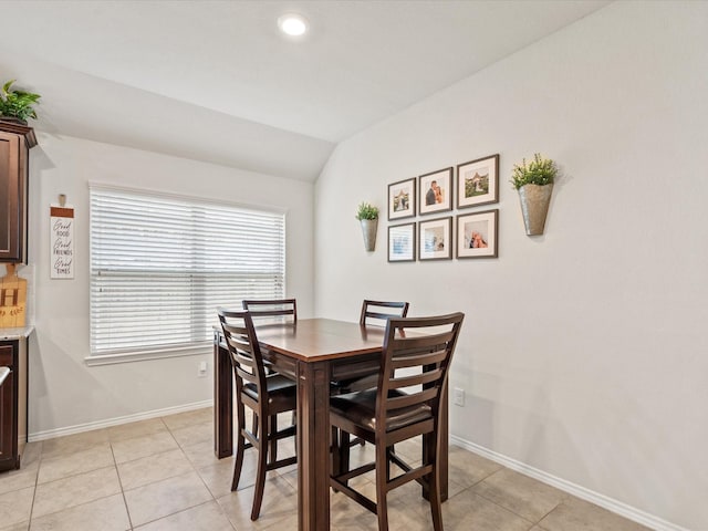 dining area featuring lofted ceiling, baseboards, and light tile patterned floors