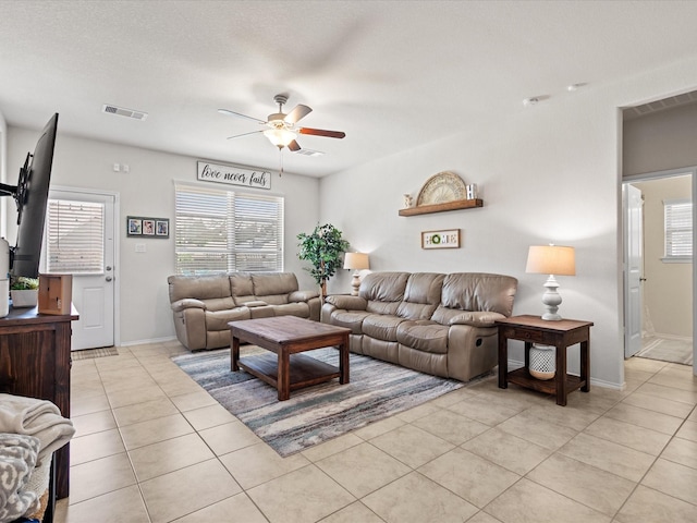 living area featuring light tile patterned floors, ceiling fan, baseboards, and visible vents