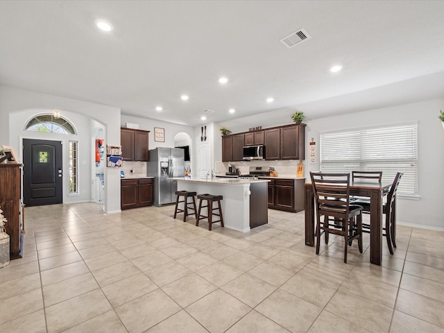 kitchen featuring stainless steel appliances, a breakfast bar area, visible vents, light countertops, and light tile patterned floors