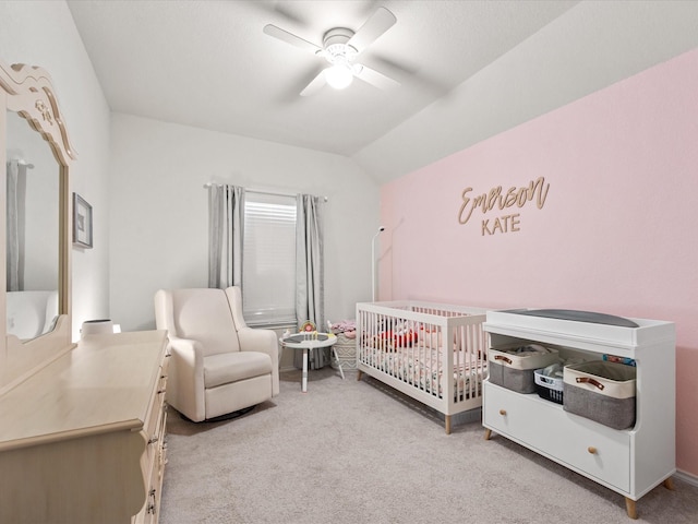 bedroom featuring vaulted ceiling, light colored carpet, a nursery area, and ceiling fan