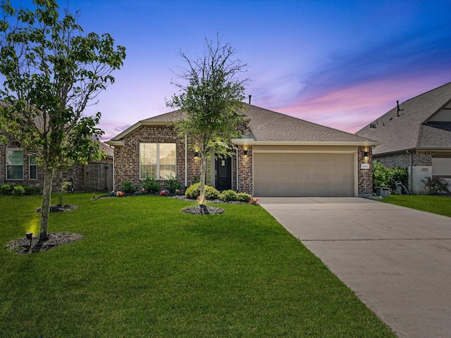 view of front of house featuring a lawn, driveway, brick siding, and an attached garage