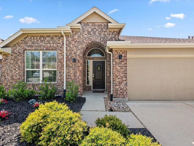 ranch-style home featuring driveway, brick siding, and an attached garage