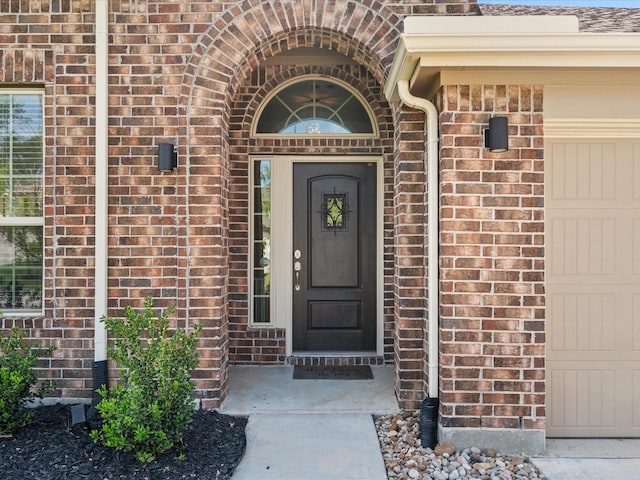 doorway to property featuring brick siding and an attached garage