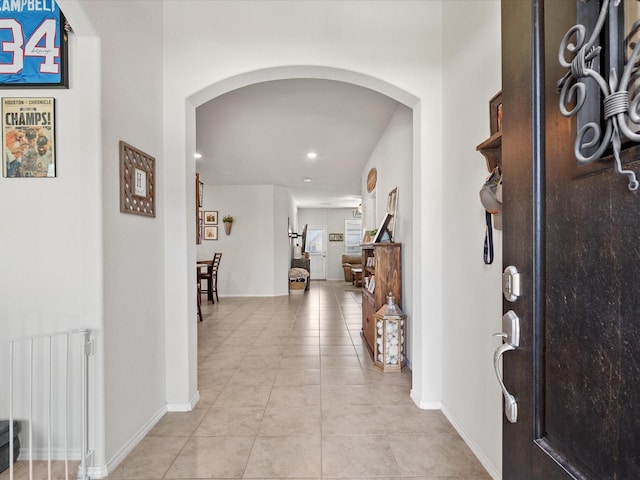entrance foyer featuring arched walkways, recessed lighting, radiator heating unit, and light tile patterned flooring