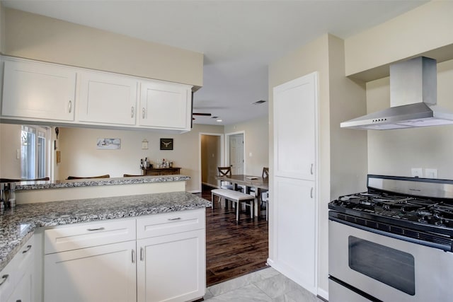 5522 Duxbury St, Houston, TX 77035 - kitchen with gas stove, wall chimney range hood, light stone countertops, white cabinets, and ceiling fan