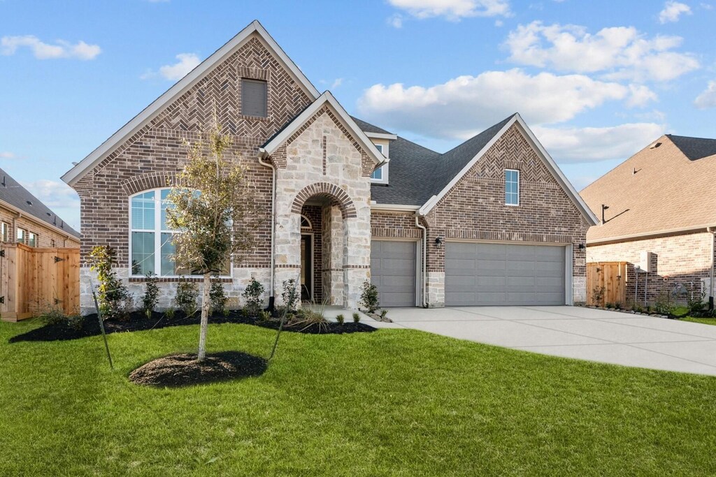 21751 Oakwood Dr, Waller, TX 77484 - french country home with a front yard, brick siding, driveway, and fence