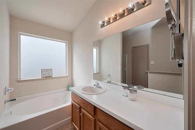 bathroom with a garden tub, lofted ceiling, and vanity