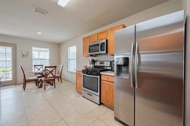 kitchen featuring light countertops, appliances with stainless steel finishes, light tile patterned floors, and visible vents