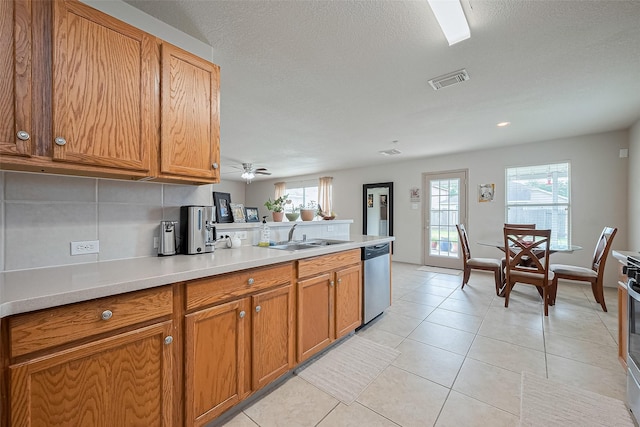 kitchen with stainless steel dishwasher, brown cabinetry, visible vents, a peninsula, and a sink