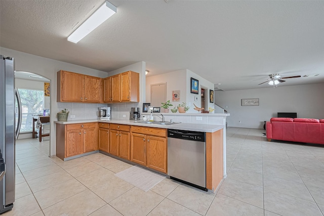 kitchen featuring light countertops, arched walkways, a sink, appliances with stainless steel finishes, and light tile patterned floors