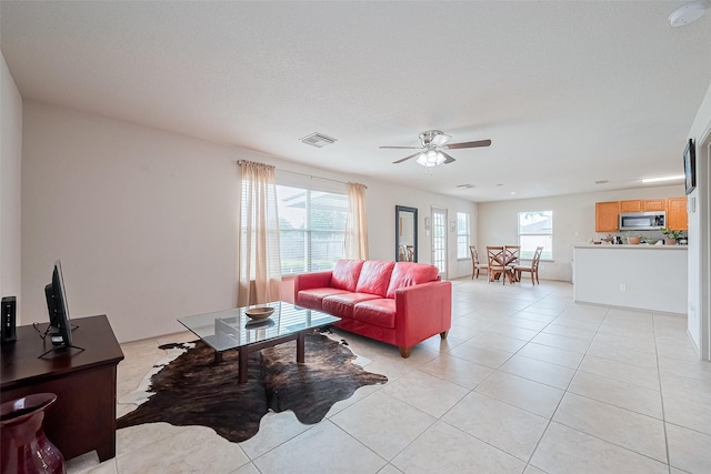 living area with light tile patterned floors, a ceiling fan, and visible vents
