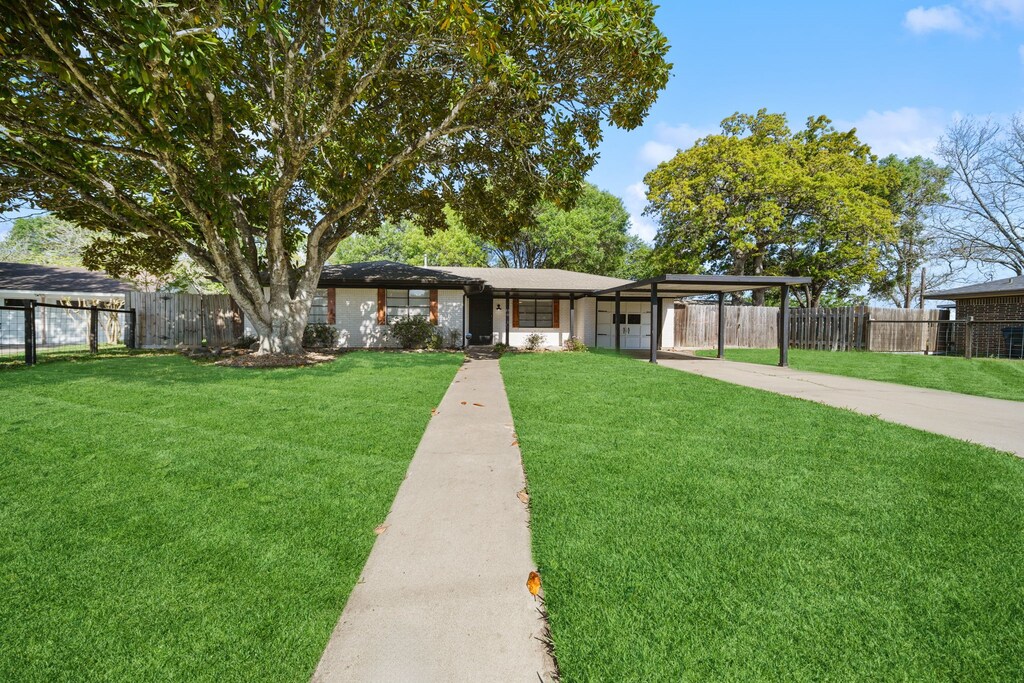 207 Munz St, Brenham, TX 77833 - view of front of house with concrete driveway, a carport, fence, and a front lawn