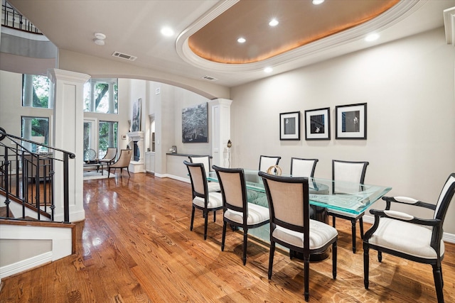 dining room featuring arched walkways, ornate columns, stairway, recessed lighting, and wood finished floors