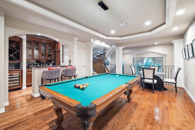 recreation room featuring light wood-type flooring, recessed lighting, a tray ceiling, a dry bar, and beverage cooler