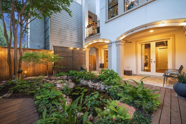 doorway to property with a balcony, french doors, fence, and stucco siding