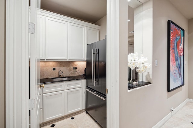 kitchen with a sink, high quality fridge, dark countertops, and white cabinets