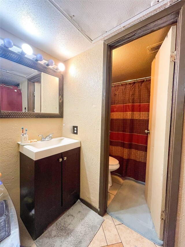 10203 Forum Park Dr Unit 114, Houston, TX 77036 - full bathroom with a textured wall, tile patterned flooring, vanity, toilet, and a textured ceiling