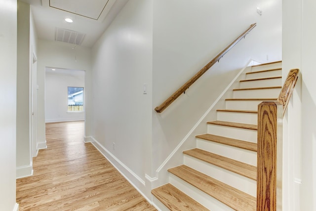 stairway with wood finished floors, attic access, baseboards, and visible vents