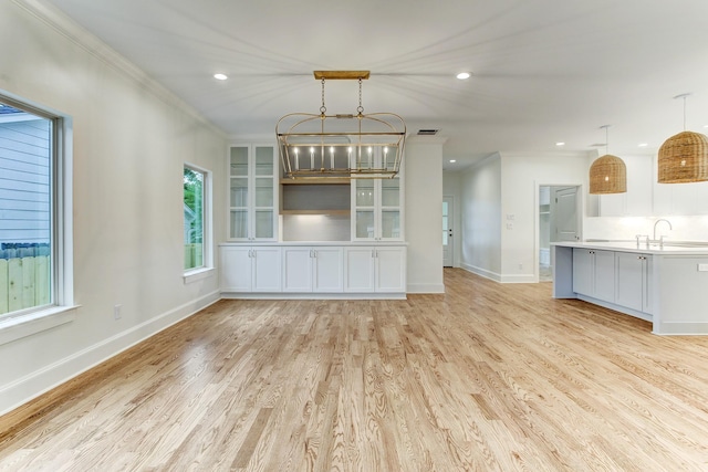 unfurnished living room featuring recessed lighting, light wood-type flooring, baseboards, and a sink
